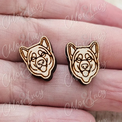 Wooden dog face stud earrings with engraved detail on a hand