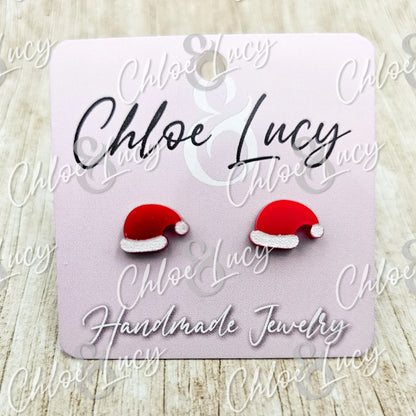 Red Santa hat stud earrings on a pink handmade jewelry card
