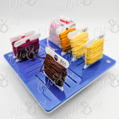 Colorful embroidery floss bobbins organized on a blue thread holder tray