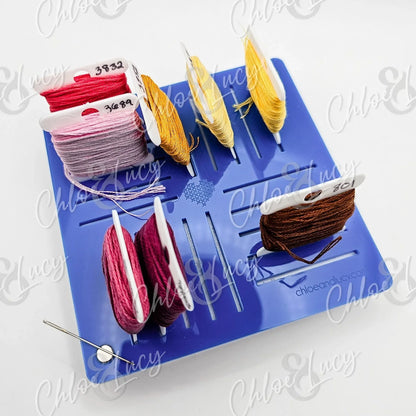 Embroidery floss organizer with colorful thread bobbins and a needle on a blue holder